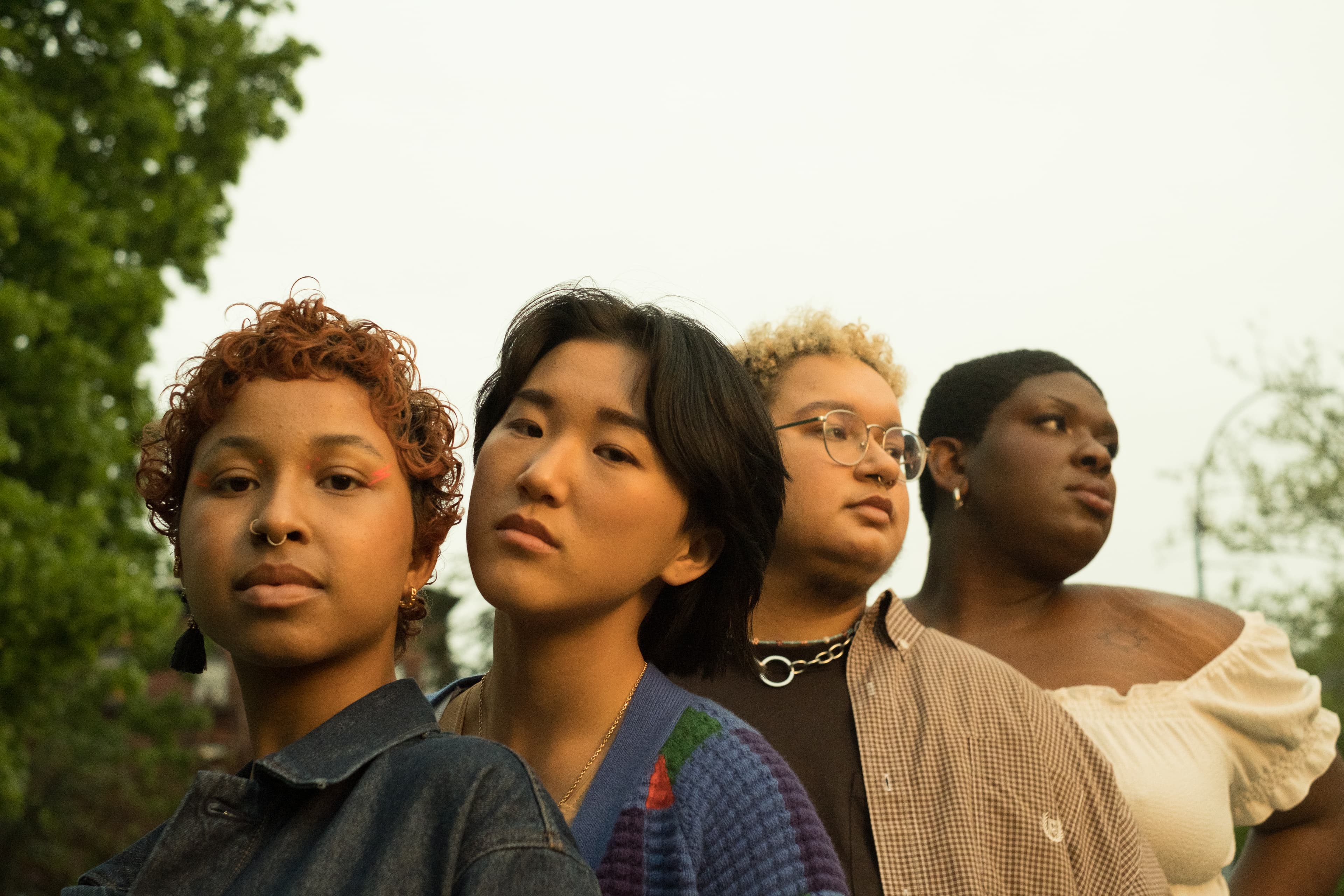 Four friends of different backgrounds standing close together outdoors